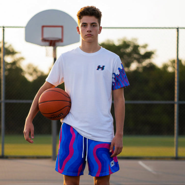 Person holding a basketball on a basketball court wearing a white and blue outfit with logos.